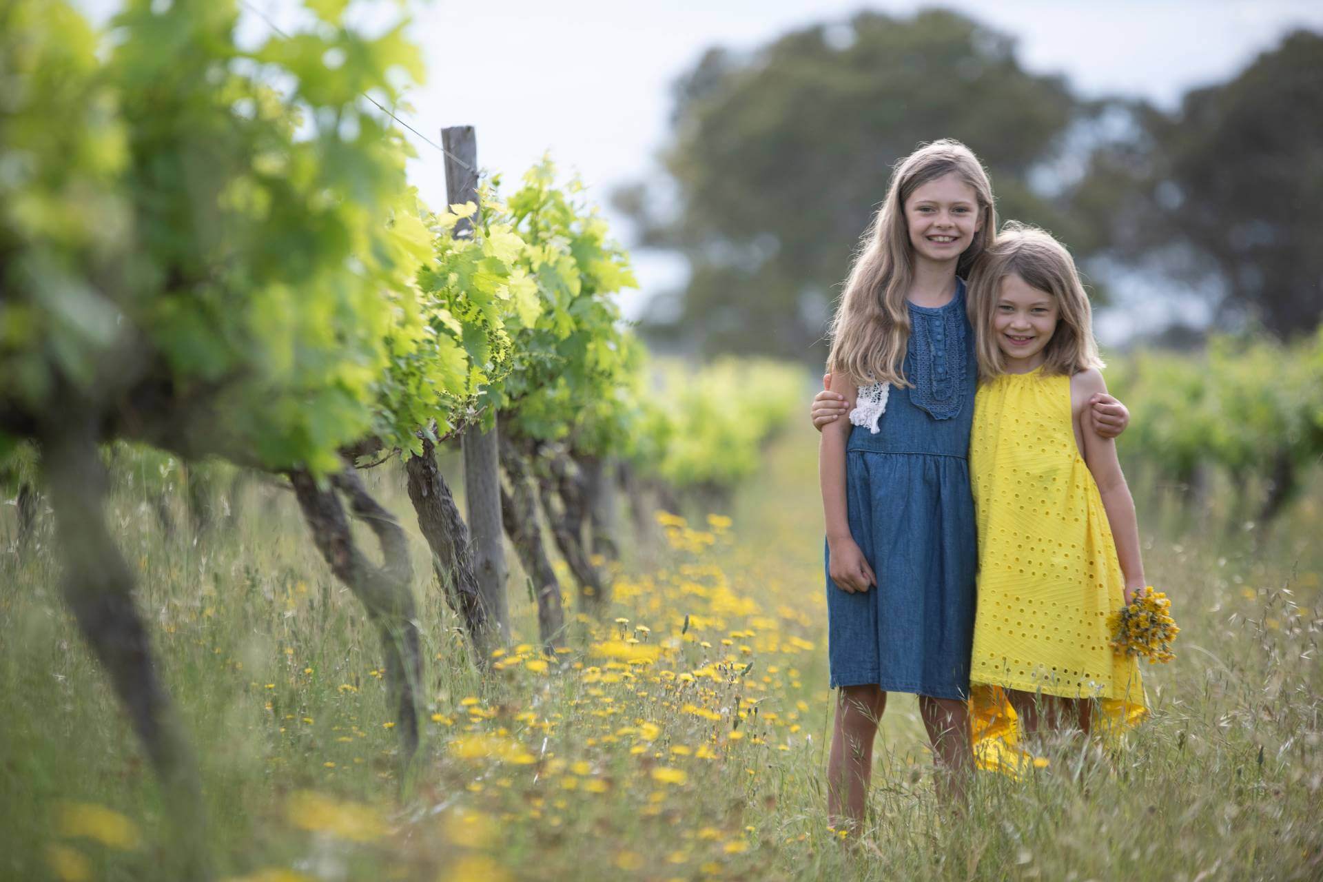 Lucy and Alice standing together in the organic vineyard when they were younger
