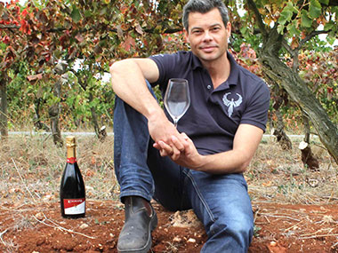 Dru sitting on the soil profile cutting with a glass and a bottle of red wine
