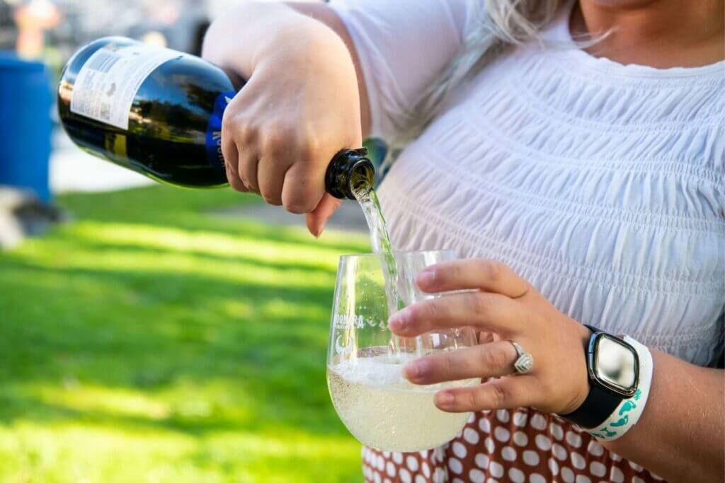 A woman pouring Guardian Angel Sparkling Chardonnay from Koonara Wines into a glass.